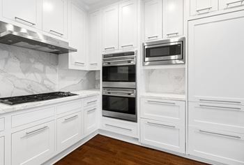 a kitchen with white cabinets and stainless steel appliances at HIGHGROVE, Stamford, CT